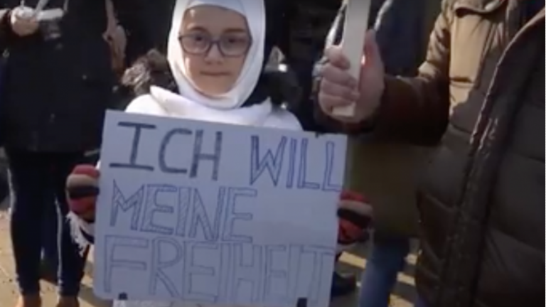 Ein Mädchen mit Hijab mit dem Schild: ich will meine Freiheit