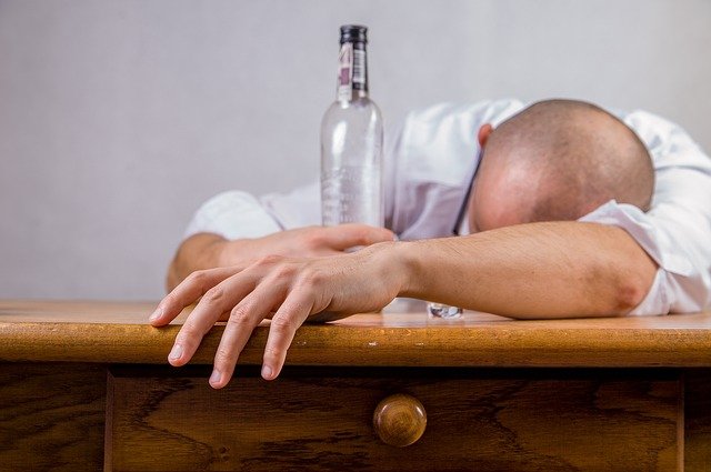 Ein Betrunkener Mensch eingeschlafen mit der Flasche in Hand